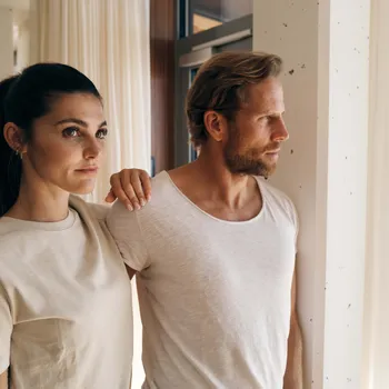 Philosophy Couple in casual beige clothing gazing out a bright window in modern interior